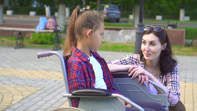 Teenager disabled in a wheelchair talking to a girl.Slow mo