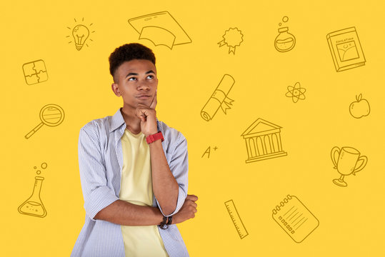 Higher education. Curious handsome student standing alone and thoughtfully looking into the distance while imagining his life after graduation - Powered by Adobe