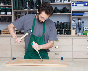 Hands of carpenter with chisel in the hands on the workbench in carpentry