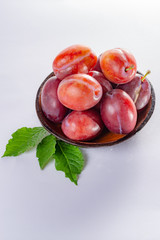 Group of ripe oval Victoria plums from England on white background with leaves