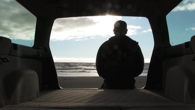 Person sitting at the back of his car gets a beautiful beach view at the Pacific Ocean on sunny day.