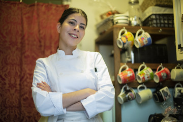 chef latina en cocina con tazas de fondo
