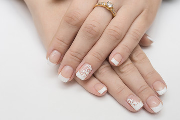 Hands with manicured nails covered with pink nail polish on fur background
