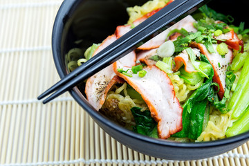 Yellow noodles served with sliced red pork