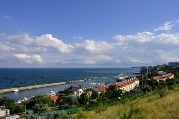 Embankment of the Black Sea. Small waves and a beautiful panorama of the sea. Classical and modern buildings. The slopes are covered with green trees. Light wind and good weather. 