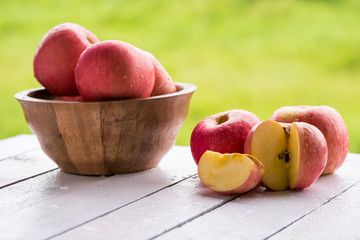 Red apples on wooden table with natural green background