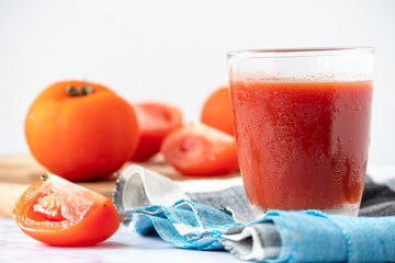 Glass of tomato juice and fresh tomatoes on marble table