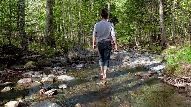 Man walking in a creek or small river on a sunny day