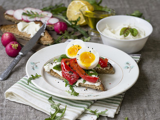 Toast with egg, red pepper, cheese and rucola on a white plate. Breakfast. Background made of linen cloth. Close up