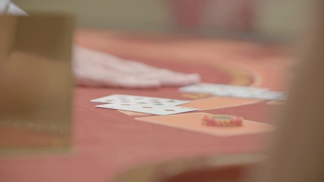Slow motion shot of cards and chips on velvet poker table in casino. Gambling, luck and addiction concept.