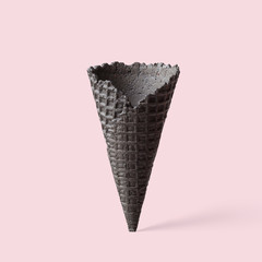 Black wafer ice cream cone on a pink background. Minimalistic concept.