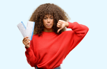 African american woman holding airline boarding pass tickets with angry face, negative sign showing dislike with thumbs down, rejection concept