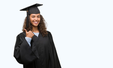 Young hispanic woman wearing graduation uniform happy with big smile doing ok sign, thumb up with fingers, excellent sign
