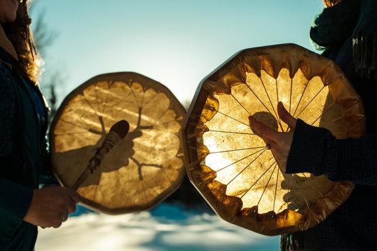 Women holding and playing their sacred drums outdoors in the wintertime