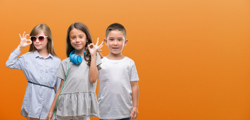 Group of boy and girls kids over orange background doing ok sign with fingers, excellent symbol © Krakenimages.com