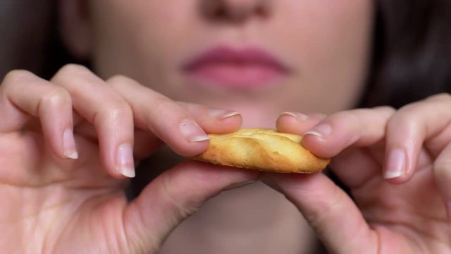 young woman breaks a cookie with her hands and eating it- slow motion