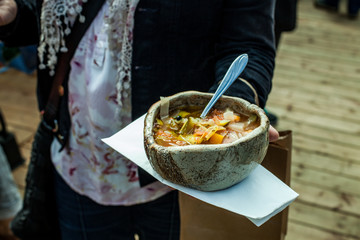 Woman holds up a huge ceramic bowl full of delicious-looking vegetable soup