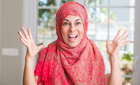 Middle aged muslim woman wearing hijab very happy and excited, winner expression celebrating victory screaming with big smile and raised hands