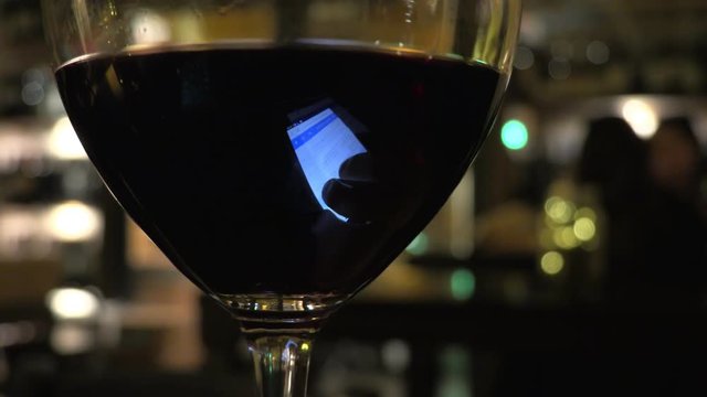 smartphone screen reflecting ob glass of wine. Communication,techomology,relax