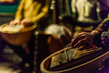 Man's hands playing kalimba with blurry musicians playing african instruments live on stage