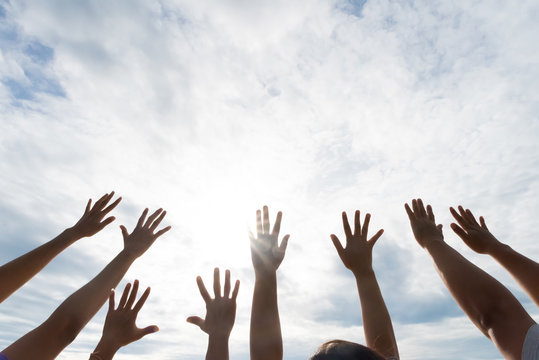 Many hands raised up against the blue sky. Friendship, Teamwork concept.