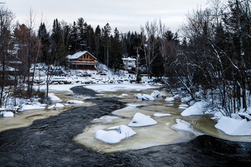 Northern river flowing around frozen rocks and icebergs in the winter time