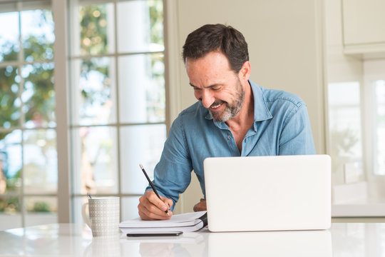 Middle age man using laptop at home with a happy face standing and smiling with a confident smile showing teeth