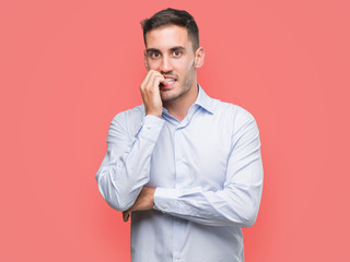 Handsome young businessman looking stressed and nervous with hands on mouth biting nails. Anxiety problem.