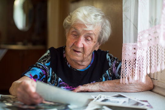 Elderly woman watching photos sitting at table.