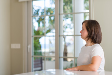 Down syndrome woman at home looking to side, relax profile pose with natural face with confident smile.