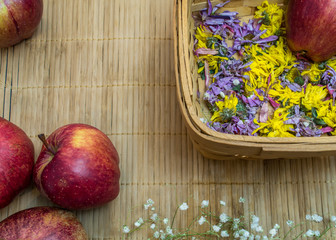 Red fruits are on bamboo tablecloth and basket with dry flowers
