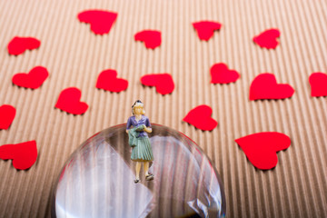 Woman figurine on half a globe with paper hearts