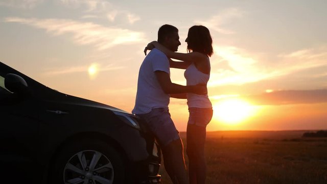 Silhouette of happiness couple stay near the new car under sky. Beautiful young couple standing near car at sunset.