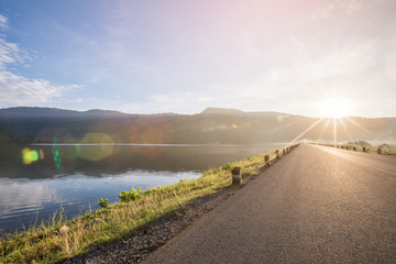 Asphalt road with reservoir on clearly blue sky and mountains.