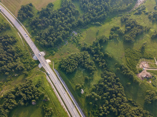 Helicopter drone shot. Aerial photography of green forest with road, green grass.
