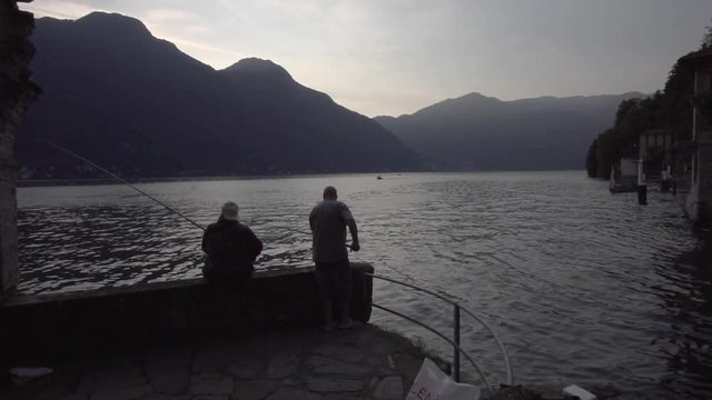 couple of fisherman in nesso como lake at sunset