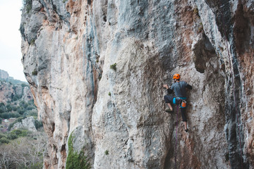 A man in helmet climbs the rock.