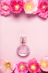 Women's perfume bottle and pink mallow flowers on pink backgroun