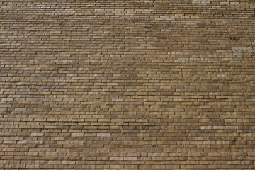 Upward view of a massive light brown brick wall background