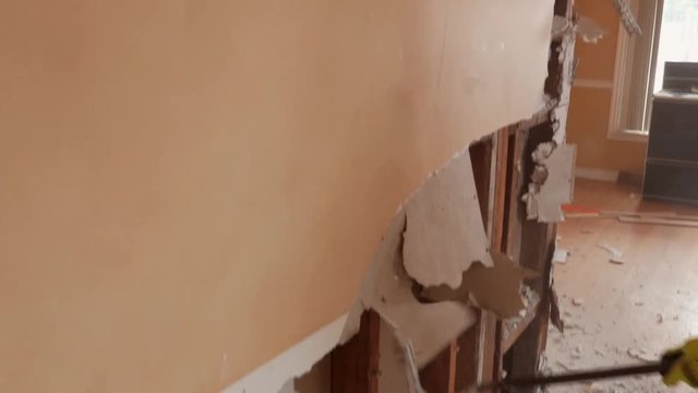 Worker in protective suit demolishes plaster wall. (with Audio)
