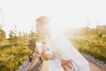 Beauty sunset light. Little baby girl wants to eat and child looking for mother's breasts in the...