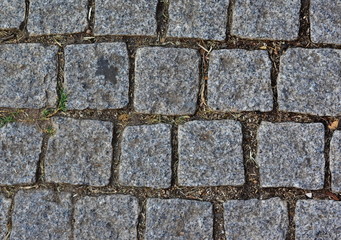 Black cobbled stone road background. Black or dark grey stone pavement texture.