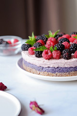 Raw vegan cake with raspberries and bluberries on white table