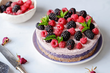 Raw vegan cake with raspberries and bluberries on white table