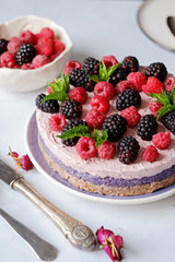 Raw vegan cake with raspberries and bluberries on white table