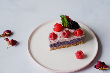 Raw vegan cake with raspberries and bluberries on white table
