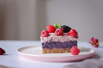 Raw vegan cake with raspberries and bluberries on white table