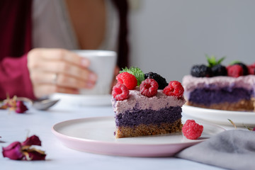 Raw vegan cake with raspberries and bluberries on white table