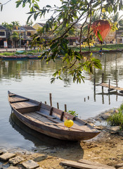 Wooden boat parked on bank of the Thu Bon River