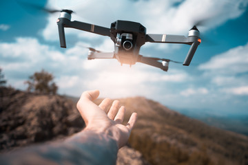 male hand catching drone on sunset. Safe quad copter landing on the pilot's palm